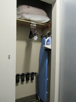 A compact storage area with a blue mattress, a hanging bag, and a metal rack with black items. - Best Western Abbeville Inn & Suites (Abbeville)
