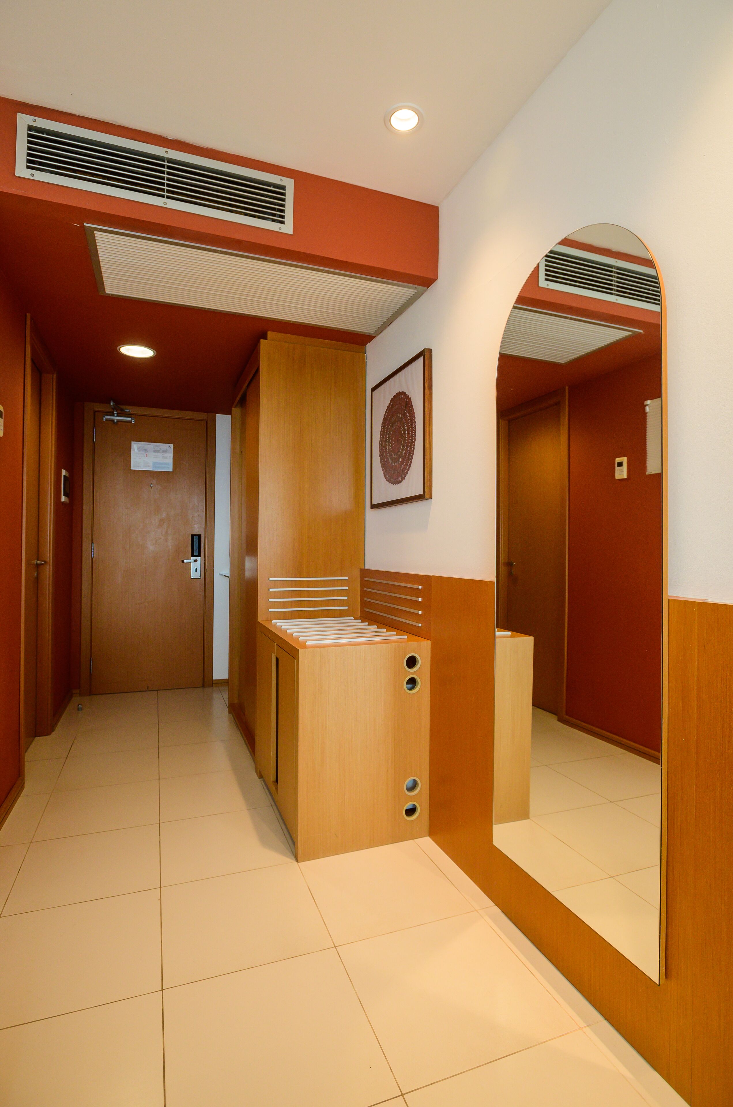 Un couloir d’hôtel avec un comptoir d’accueil en bois, un miroir et une porte sur laquelle est apposée une pancarte.