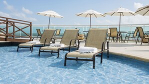 A poolside area with lounge chairs and umbrellas, a wooden deck, and a view of the ocean. - Hotel Luzeiros São Luis (São Luís)
