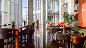 A spacious indoor area with a long table and chairs, surrounded by large windows and potted plants. - Hotel Luzeiros São Luis (São Luís)