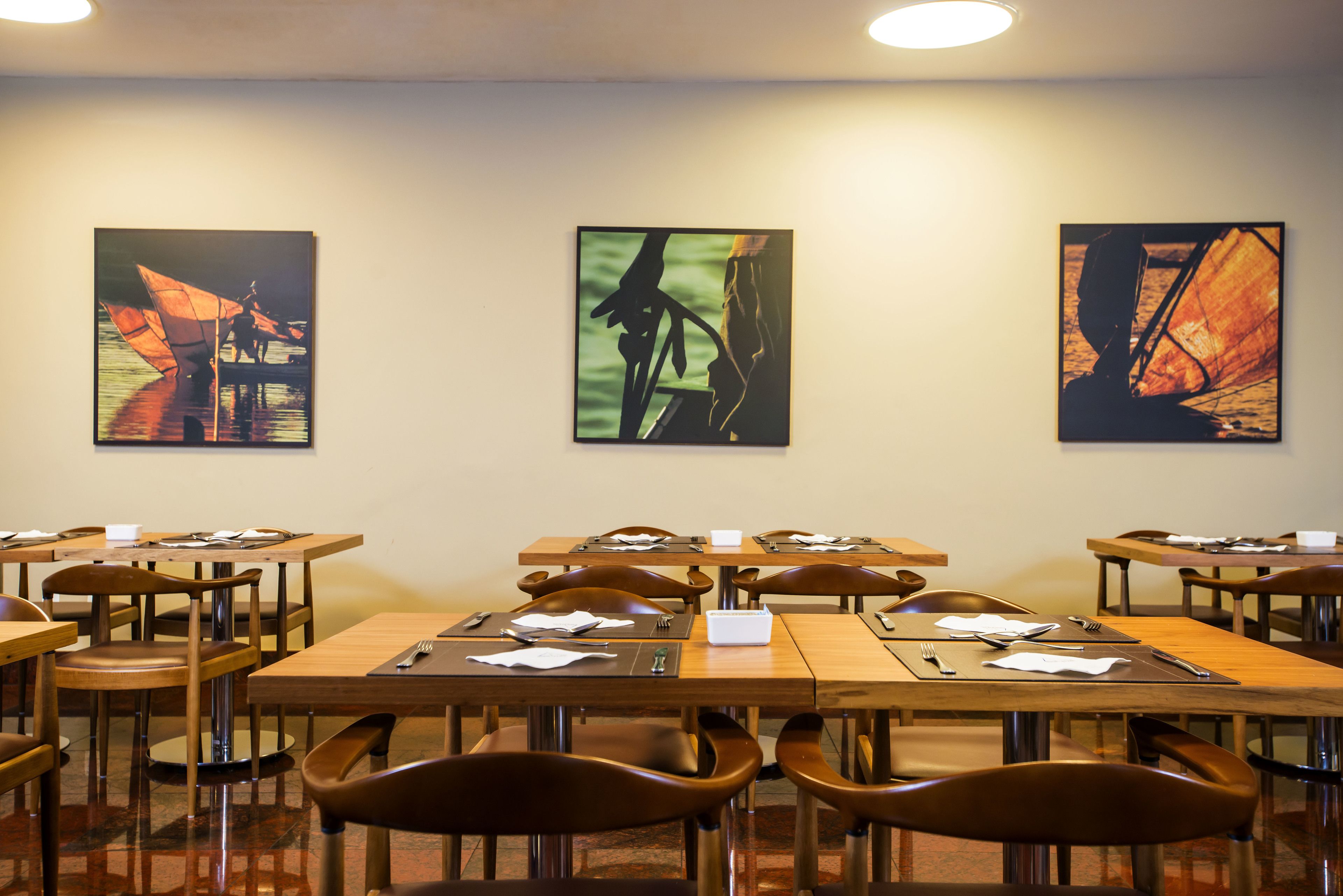 Sala de conferência com várias mesas e cadeiras, equipada com porta-nomes e materiais de escrita.