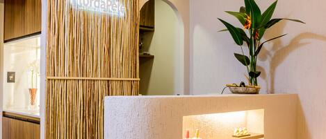 A reception area with a wooden panel wall, a reception desk with shelves of products, and a potted plant.