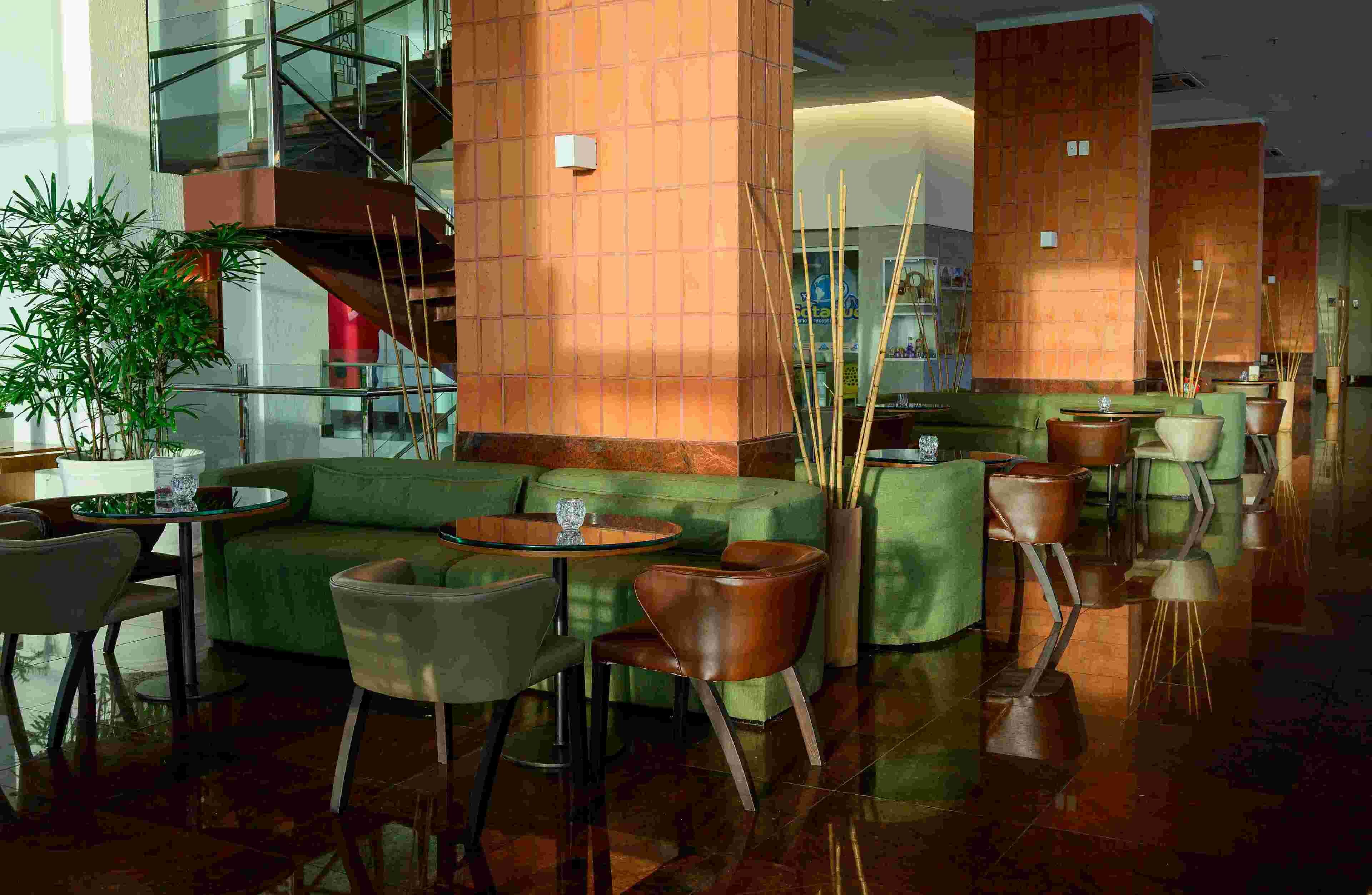 A modern lobby with a green sofa, round tables, and a staircase.
