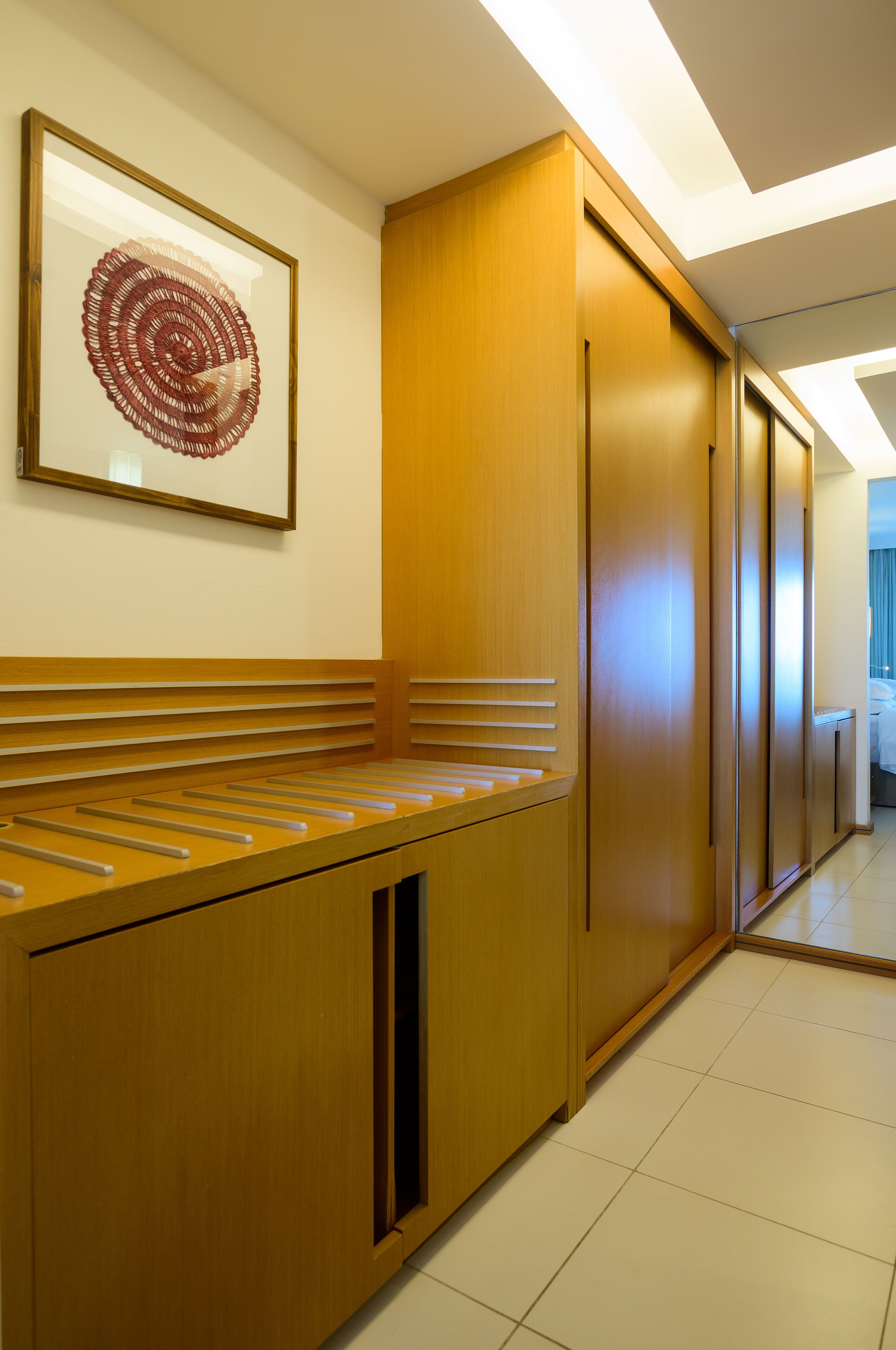 A hotel corridor with wooden paneling, a framed artwork, and a bench.