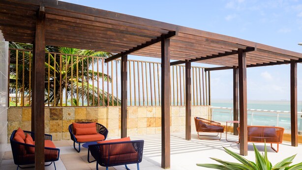 A covered outdoor seating area with wicker chairs and a potted plant. - Hotel Luzeiros São Luis (São Luís)