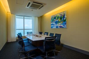 Un salón de conferencias con una gran mesa, sillas y un cuadro en la pared.