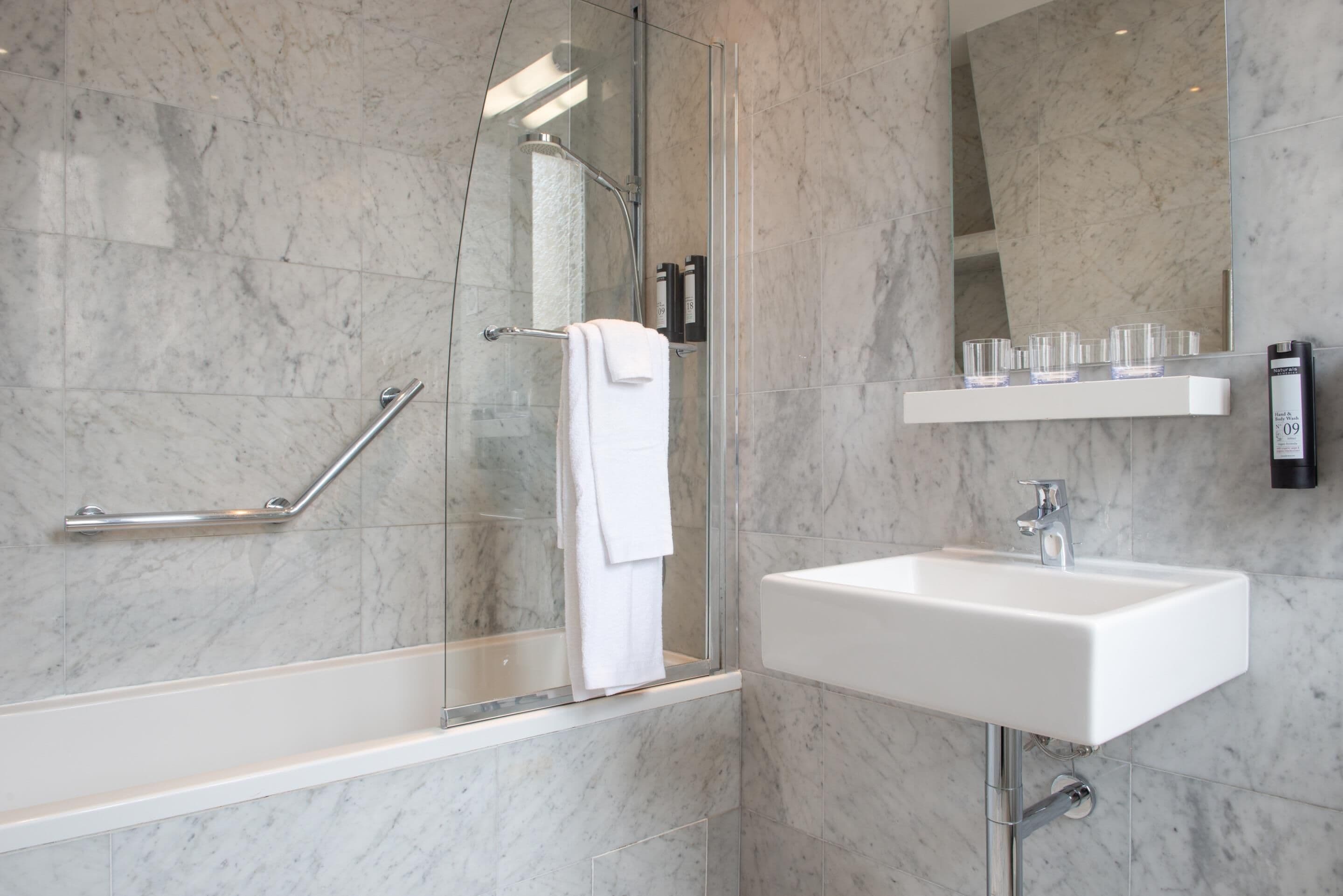 Une salle de bain moderne avec une douche à parois de verre, un lavabo blanc et un miroir au-dessus du lavabo.