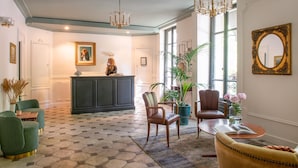 A spacious lobby with a checkered floor, a reception desk, and a large mirror. - Hotel de la Porte Dorée (Paris)