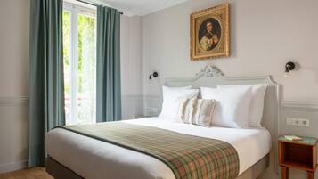 Une chambre d’hôtel avec un lit, un tableau, une fenêtre avec des rideaux et une table de chevet.