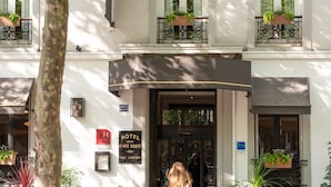 A hotel entrance with a double door, potted plants, and a sign indicating a 4-star rating. - Hotel de la Porte Dorée (Paris)
