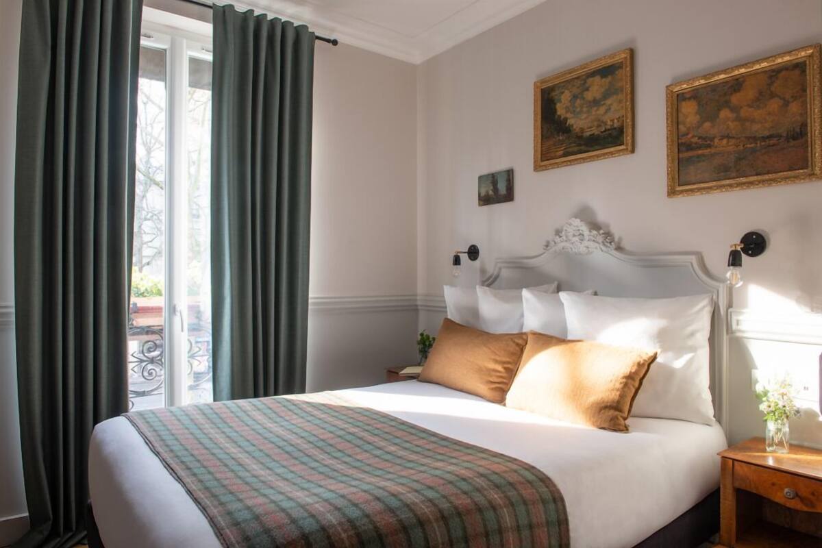 A neatly made bed with a plaid blanket, a white headboard, and two pillows.