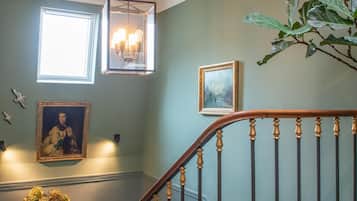 Un escalier doté d’une rampe en bois et de balustres noires, menant à un palier où se trouvent une table et un vase de fleurs.