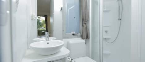 A modern bathroom with a white sink, toilet, and glass shower enclosure.