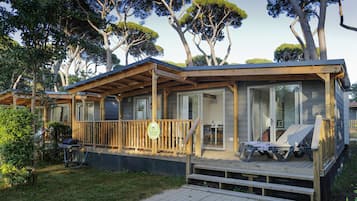 A wooden deck with a covered seating area and a grill.