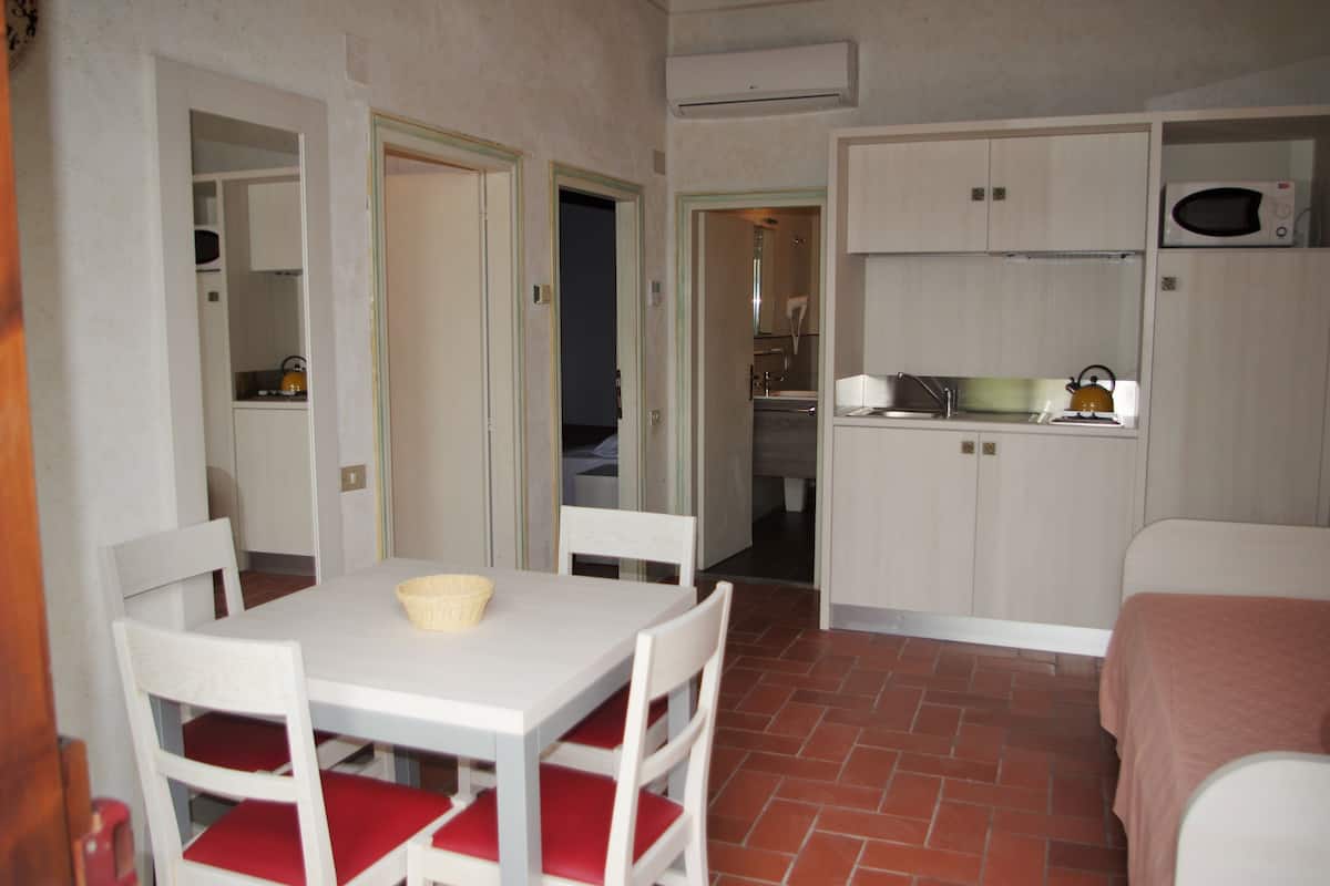 Una habitación compacta con mesa y sillas, una kitchenette y una cama.