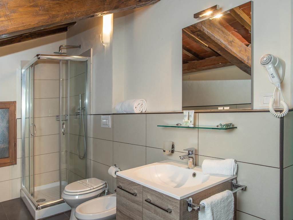 A modern bathroom with a glass shower enclosure, a white sink, and a hairdryer on the wall.