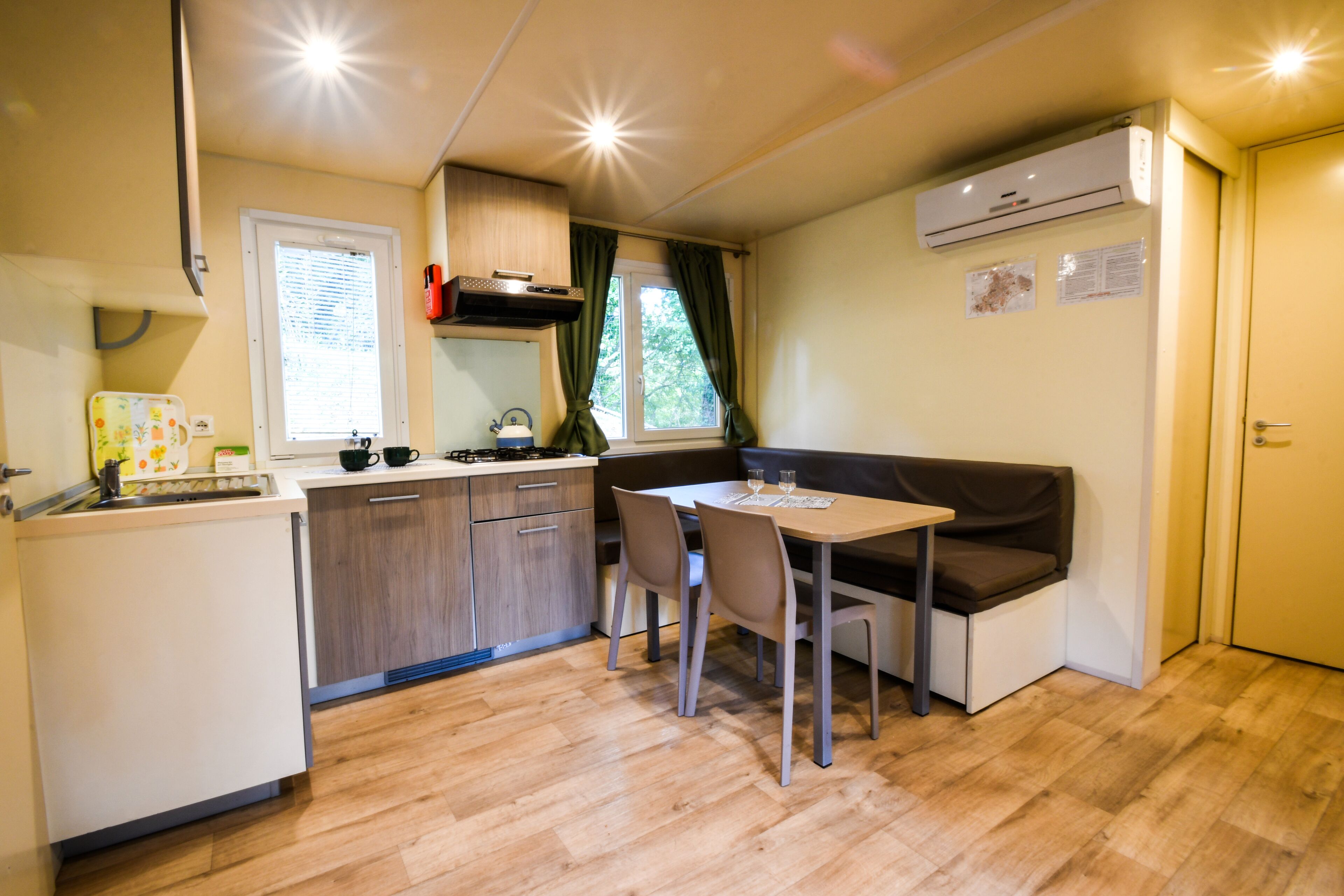 Una cocina compacta con comedor, que incluye una mesa, sillas, horno empotrado y una ventana con cortinas.