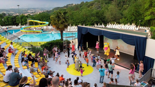 Un área de piscina con tobogán de agua y escenario para espectáculos.