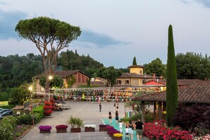 A courtyard with a central open space, surrounded by buildings with traditional architecture, and a variety of plants and flowers.