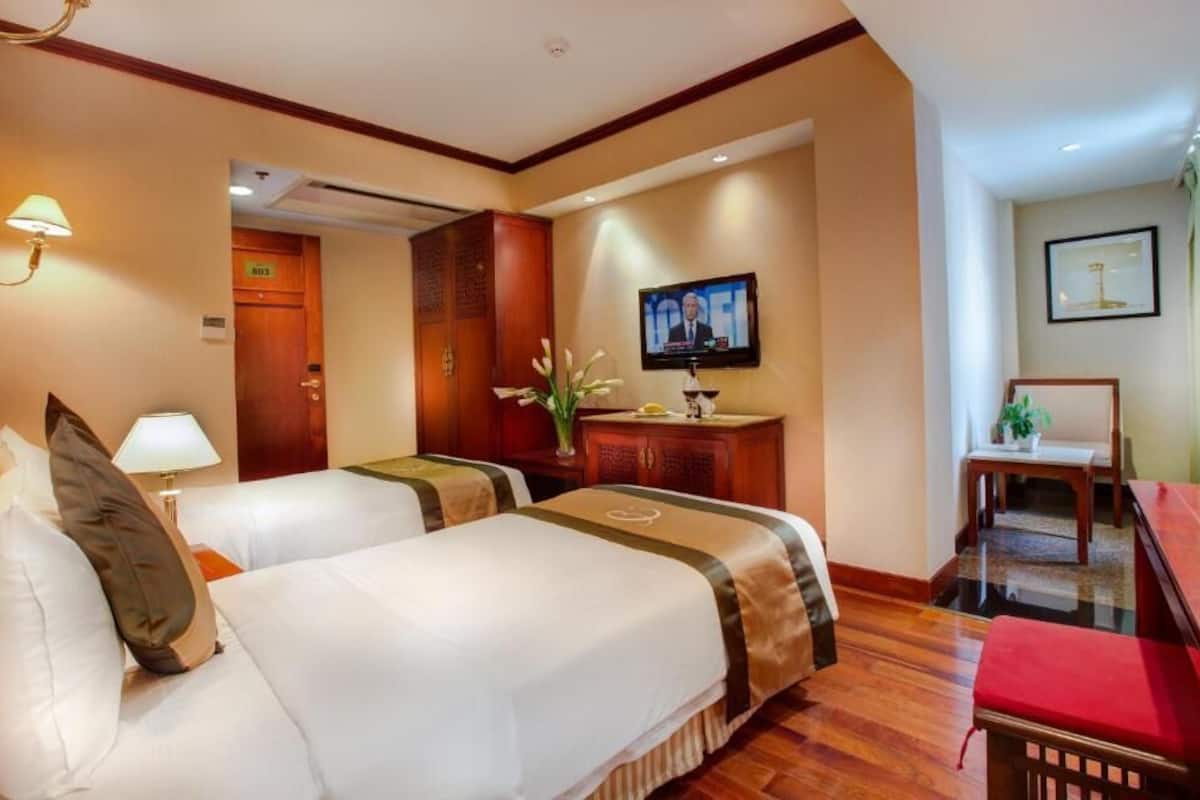 Habitación de hotel con dos camas, una televisión, un escritorio y una silla.