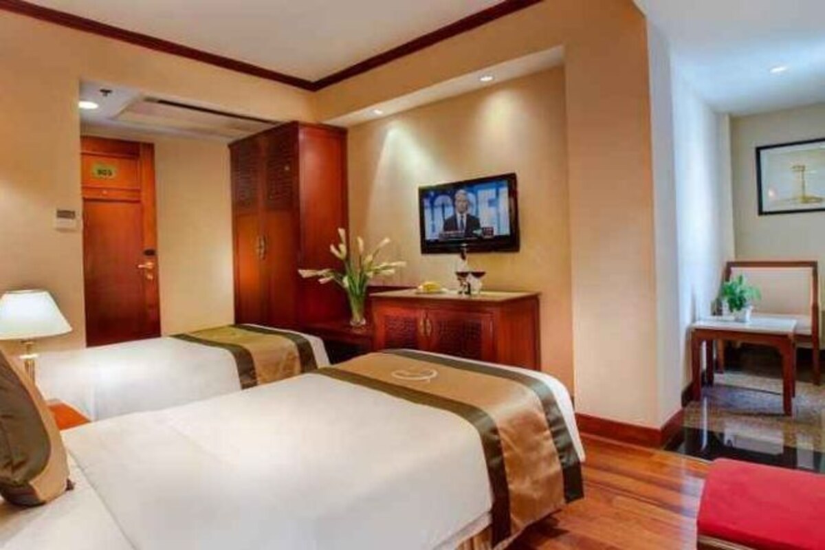 Habitación de hotel con dos camas, televisión, escritorio y una silla.