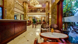 A hotel lobby with a marble floor, a chandelier, a reception desk, and a seating area with striped chairs. - Conifer Boutique Hotel (Hanoi)