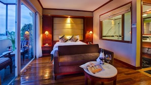 A hotel room with a bed, a small table with a magazine and wine glasses, a sofa, and a large mirror. - Conifer Boutique Hotel (Hanoi)