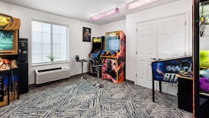A room with arcade games, a window, a radiator, and a door. - Candlewood Suites Cape Girardeau by IHG (Cape Girardeau)