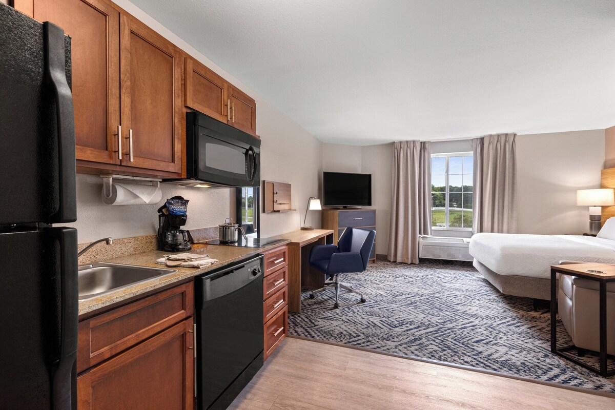 Una habitación de hotel con kitchenette, cama, escritorio y televisión.
