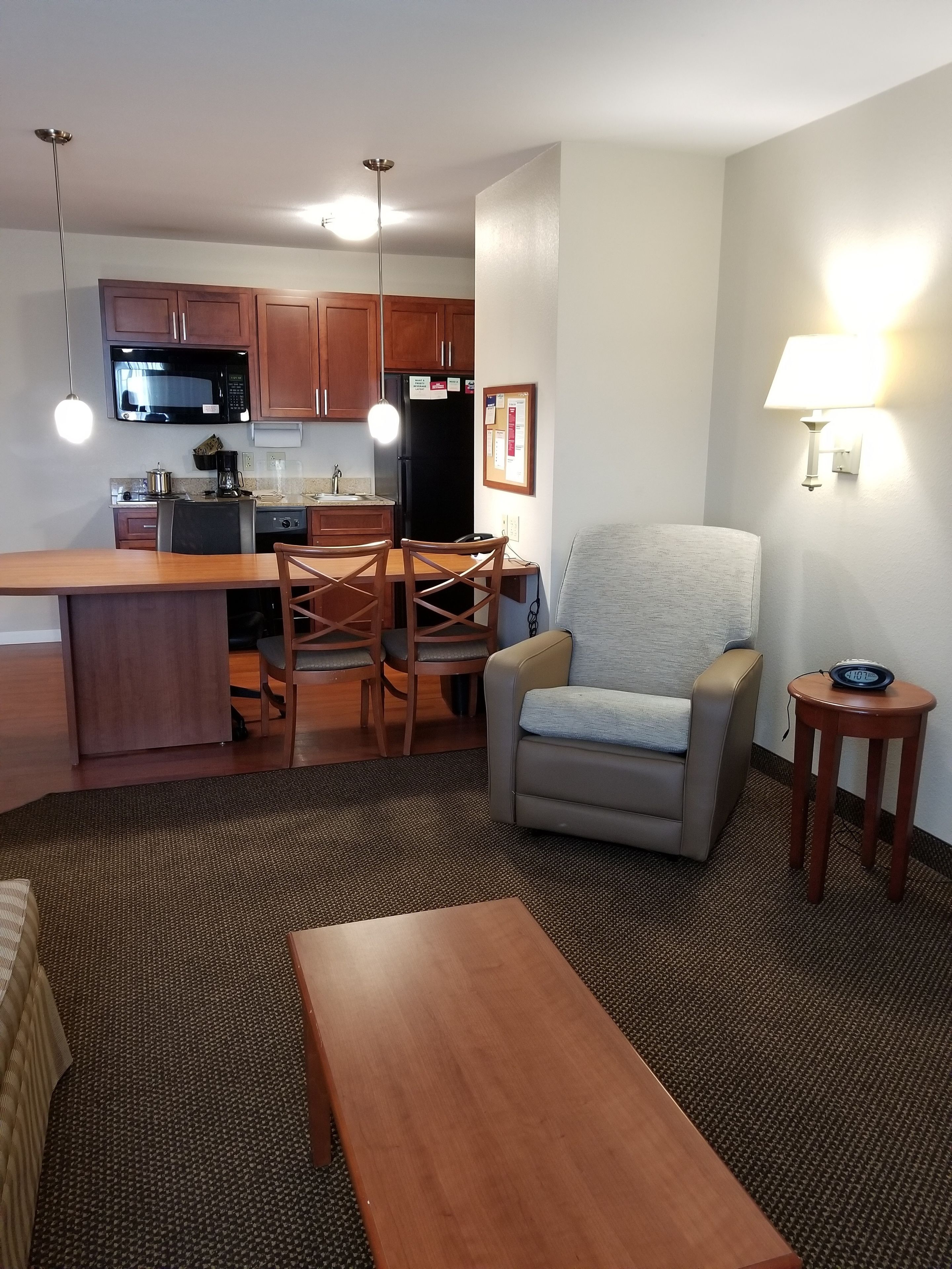 A compact living space with a kitchenette, a dining area, a sofa, a small table, and a lamp.