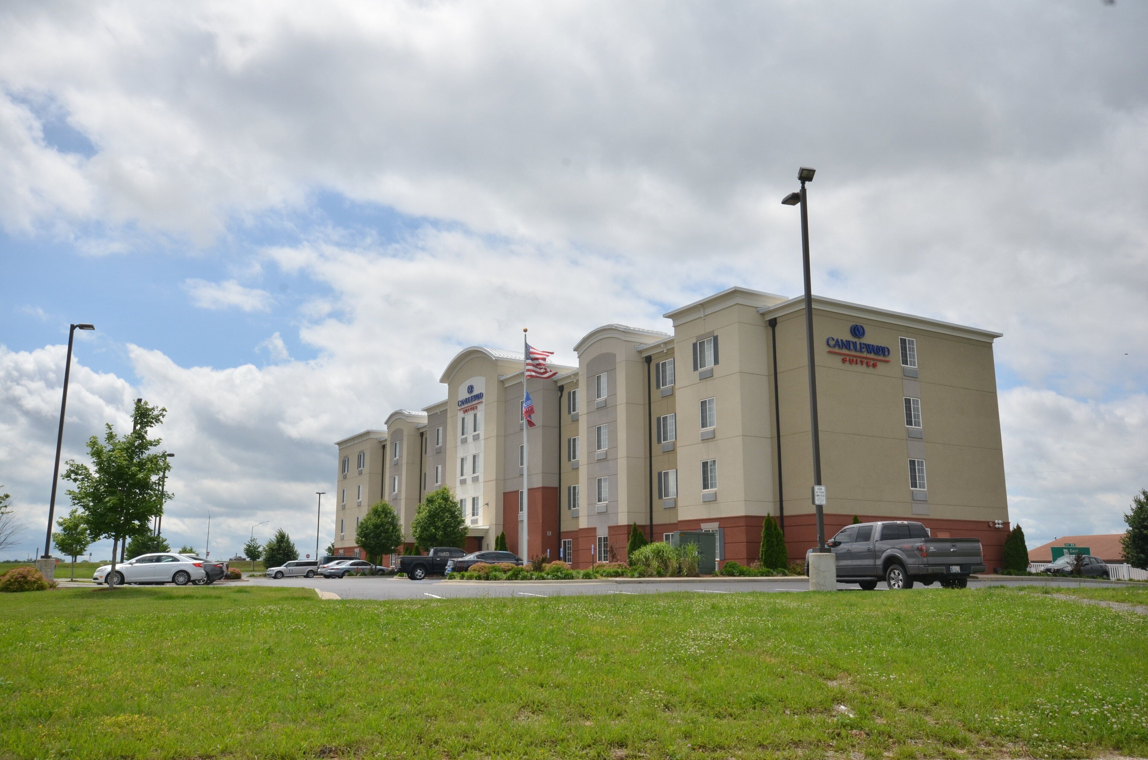 A hotel with multiple floors, a flag, and a parking lot.