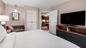 Een hotelkamer met een bed, televisie, bureau en stoel.