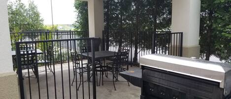 Un patio exterior con una parrilla, mesas y sillas.