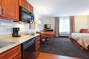 A hotel room with a kitchenette, a bed, a desk with a chair, a television, and a window with curtains. - Candlewood Suites Cape Girardeau by IHG (Cape Girardeau)