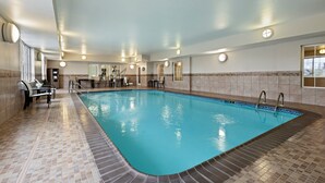 An indoor swimming pool with tiled flooring, a seating area with chairs, and a staircase leading to a door. - Candlewood Suites Cape Girardeau by IHG (Cape Girardeau)
