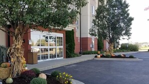 A hotel entrance with a large tree, a well-maintained garden with various plants and flowers, and a parking lot. - Candlewood Suites Cape Girardeau by IHG (Cape Girardeau)
