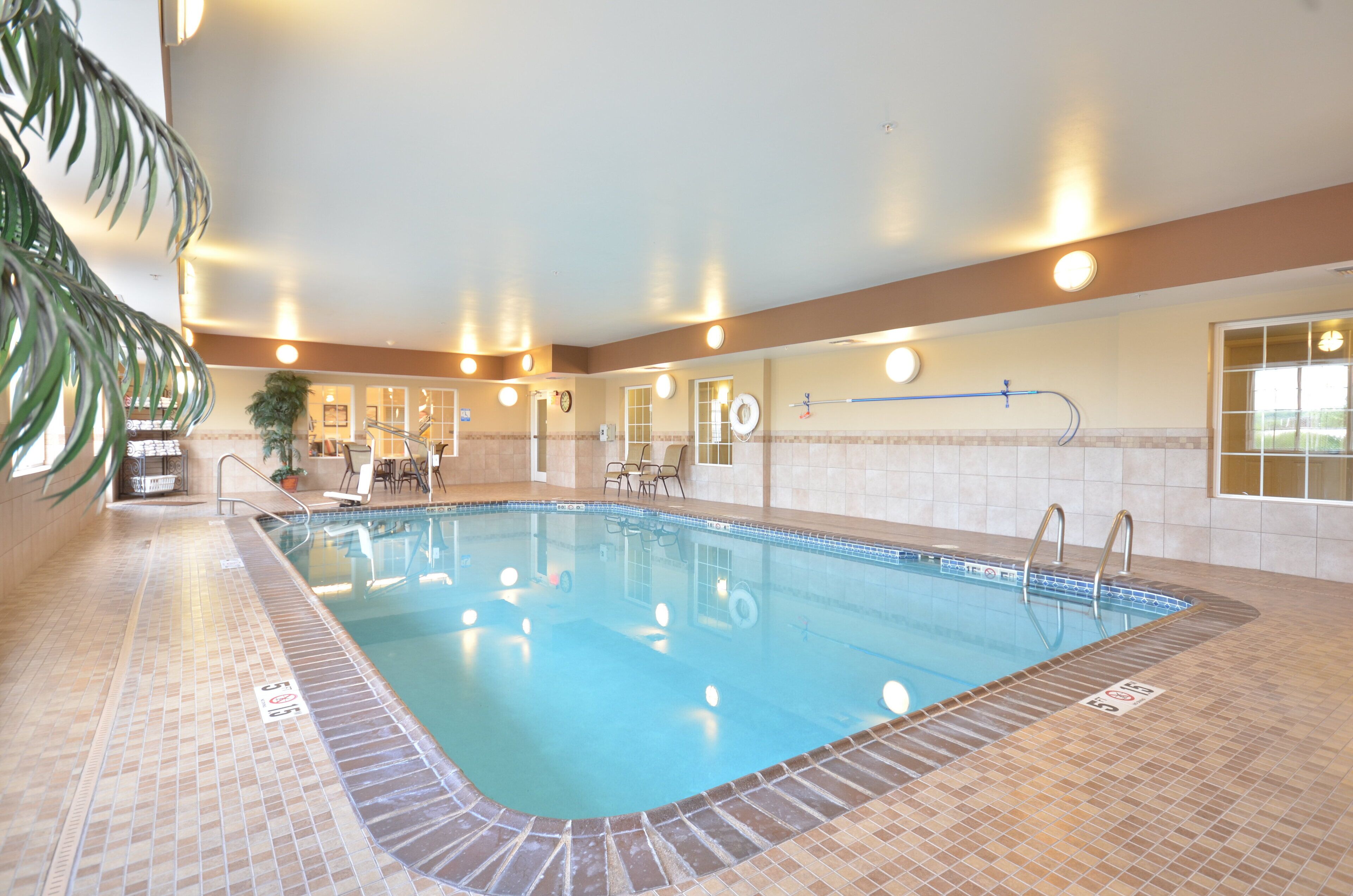 An indoor swimming pool with clear water, surrounded by tiled walls and a tiled floor.