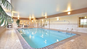 An indoor swimming pool with clear water, surrounded by tiled walls and a tiled floor.