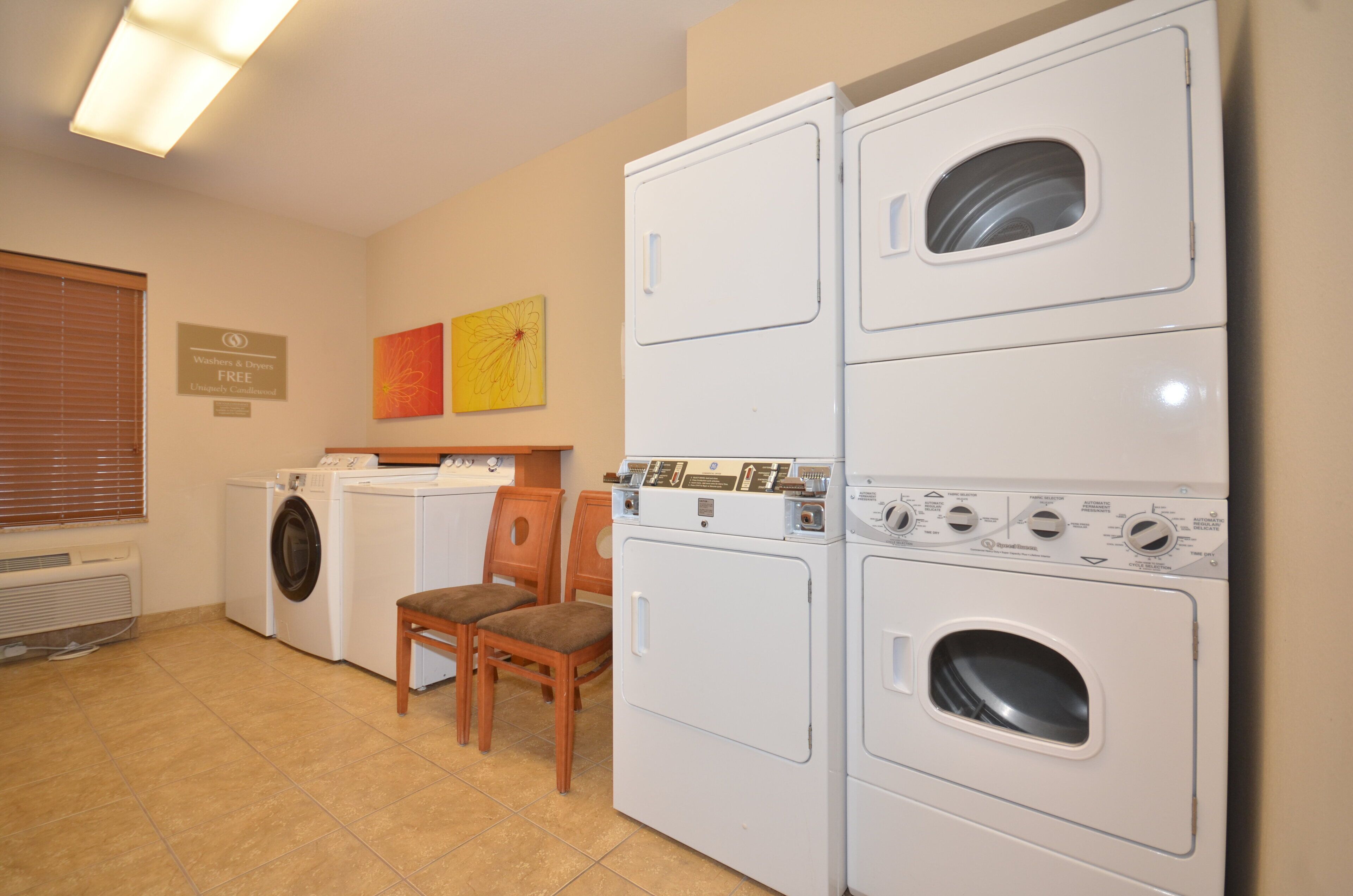 A laundry room with stacked washers and dryers, a chair, and a sign indicating free use.