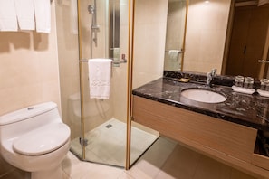 A modern bathroom with a glass-enclosed shower, a white toilet, a marble sink, and a wooden vanity. - Guide Hotel Taipei Chongqing (Taipei)