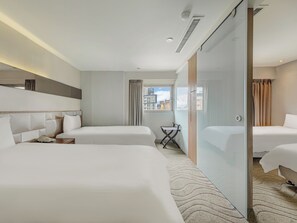Habitación de hotel con dos camas, un escritorio pequeño y vistas a la ciudad.