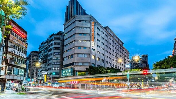Un hôtel à plusieurs étages, doté d’un design moderne, qui se distingue par une enseigne verticale imposante et une grande façade vitrée.