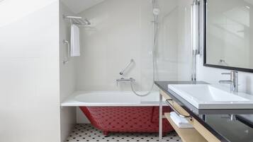 Un baño moderno con una bañera independiente, una ducha con mampara de vidrio y un espejo grande sobre el lavabo.