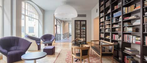 Un espace de lecture spacieux, doté d’une grande bibliothèque, de sièges confortables et offrant une vue dégagée grâce à une grande fenêtre.