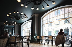 Una cafetería espaciosa con techos altos, diversas zonas de estar y grandes ventanales que dejan entrar la luz natural.