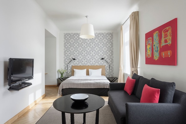 Una habitación de hotel moderna con una cama, un sofá, un televisor y un cuadro en la pared.