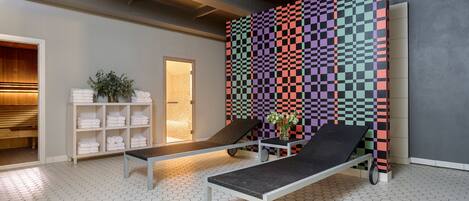 Un moderno espacio de spa con una pared estampada en cuadros, una tumbona y un estante con toallas.