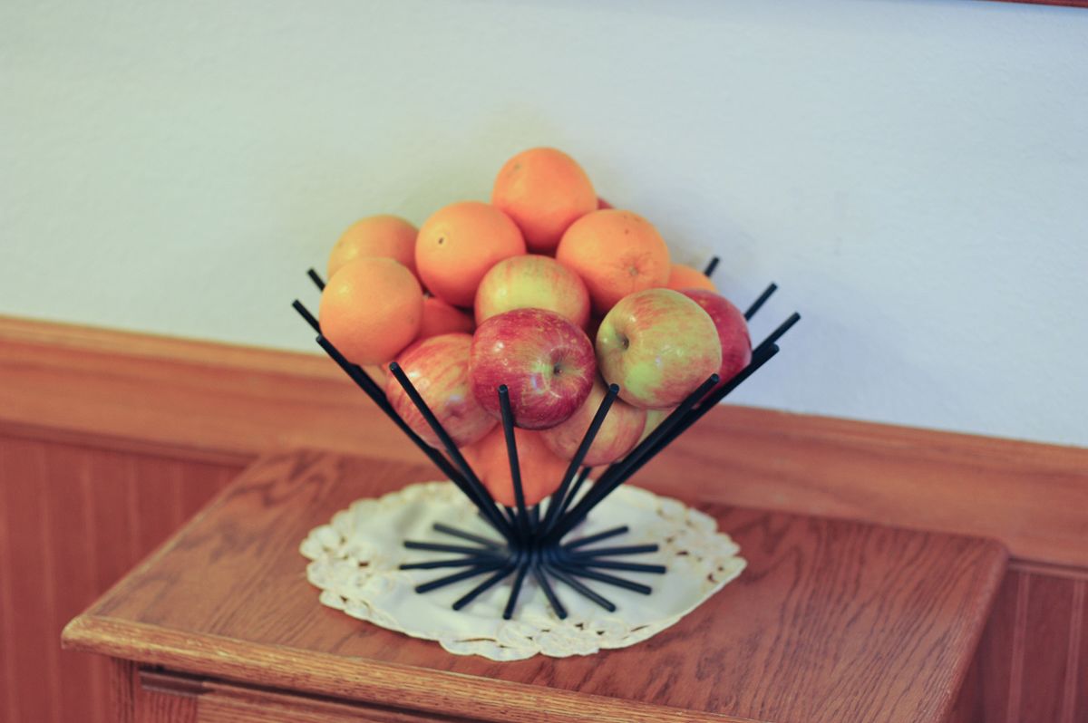 Una mesa de madera con una composición de frutas que incluye manzanas y naranjas.