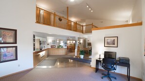 A hotel lobby with a reception desk, a staircase, a dining area, and a computer desk. - River Valley Inn & Suites (Osceola)