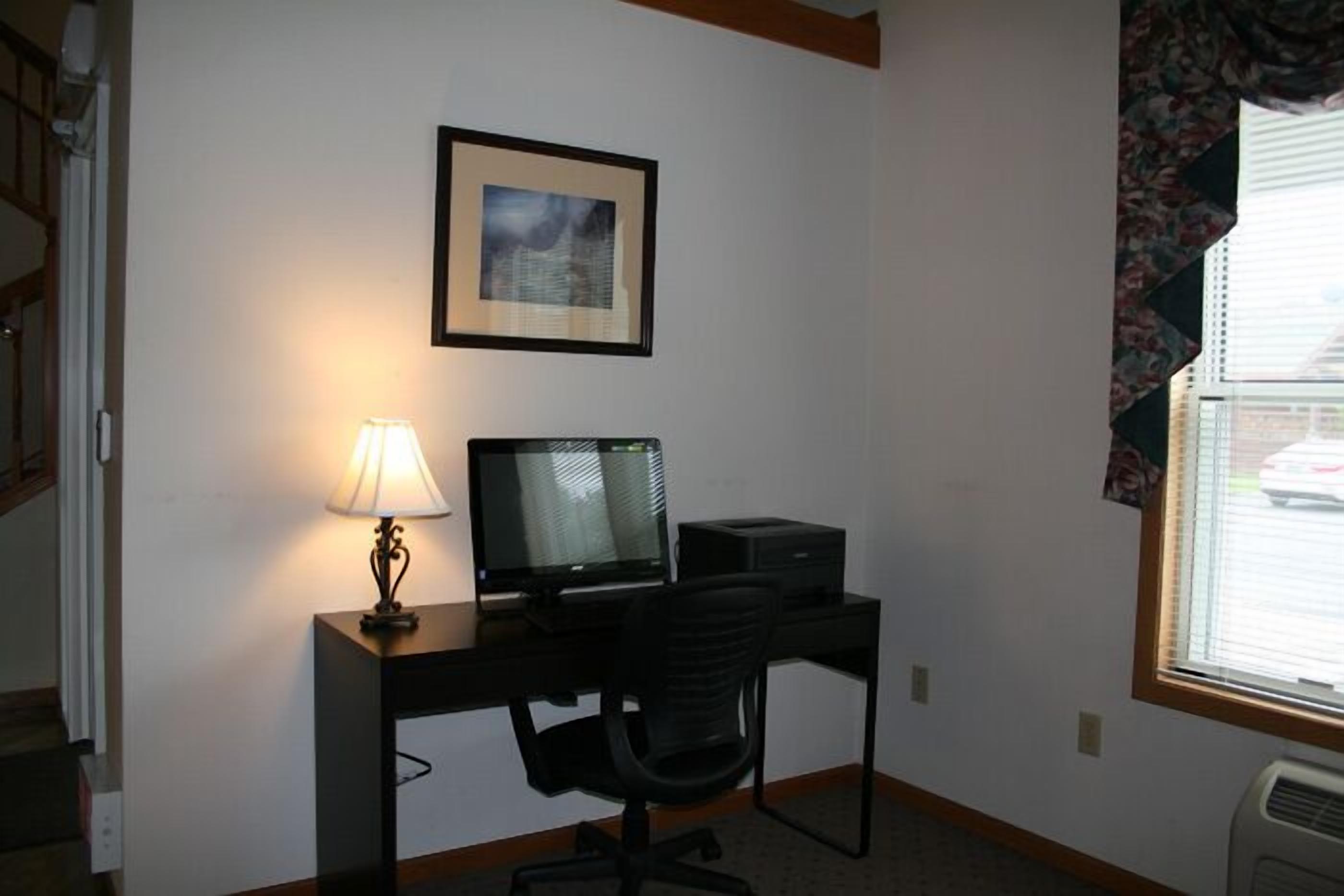 A small office space with a desk, chair, computer, and lamp.